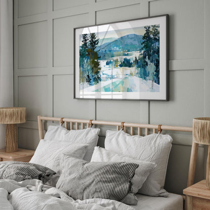 Framed winter landscape painting featuring snow, evergreen trees, and blue-green mountains, displayed above a bed with white linens and striped pillows in a modern, neutral-toned bedroom with wood accents and soft natural light.