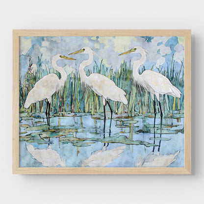 Framed artwork of three white birds standing in water with a natural background.