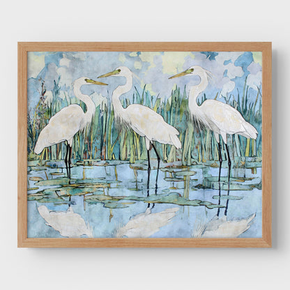 Framed artwork of three white birds standing in water with a natural background.