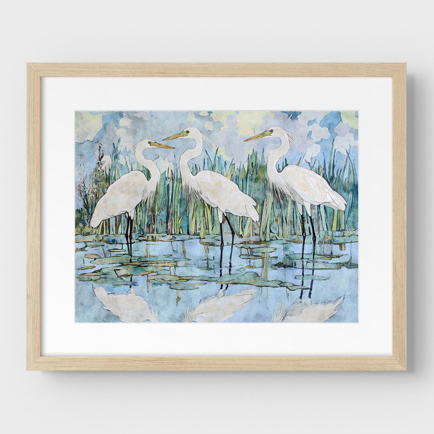 Framed artwork of three white birds in a natural setting with a light wooden frame.