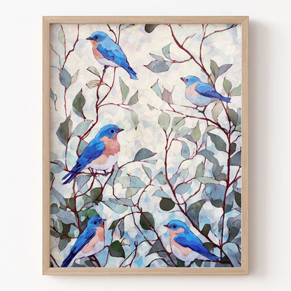 Framed artwork of blue birds on branches with leaves on a white wall