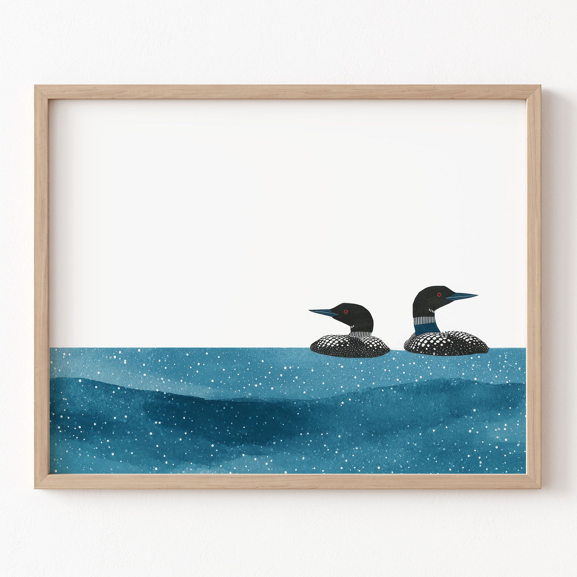 Framed artwork of two loons on a blue water surface with a white background