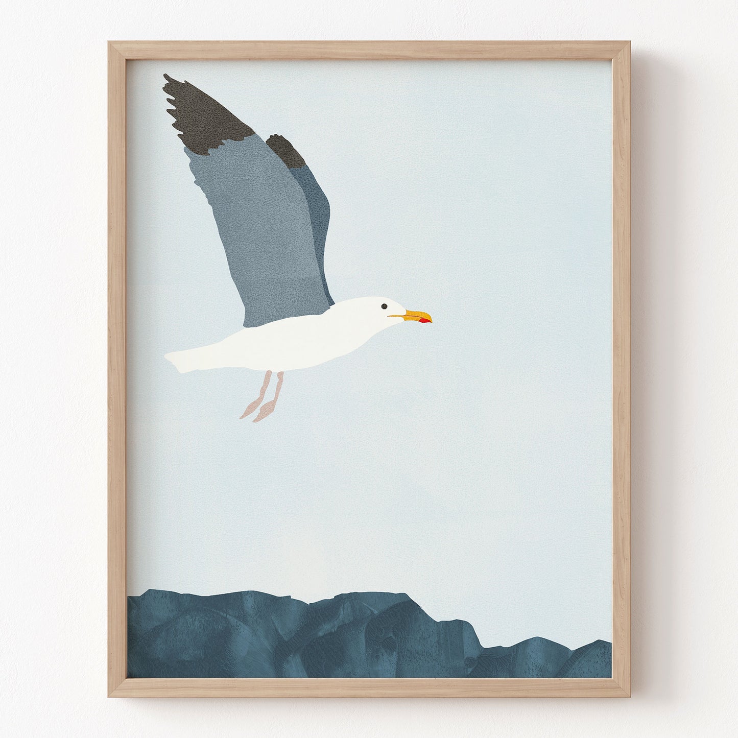 Framed artwork of a seagull flying over water on a light blue background