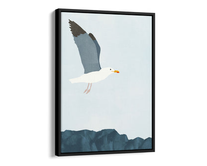 Black framed canvas illustration of a seagull soaring above a rocky shoreline, with its wings spread wide against a pale blue sky.