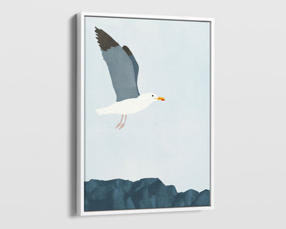 White framed canvas illustration of a seagull soaring above a rocky shoreline, with its wings spread wide against a pale blue sky.