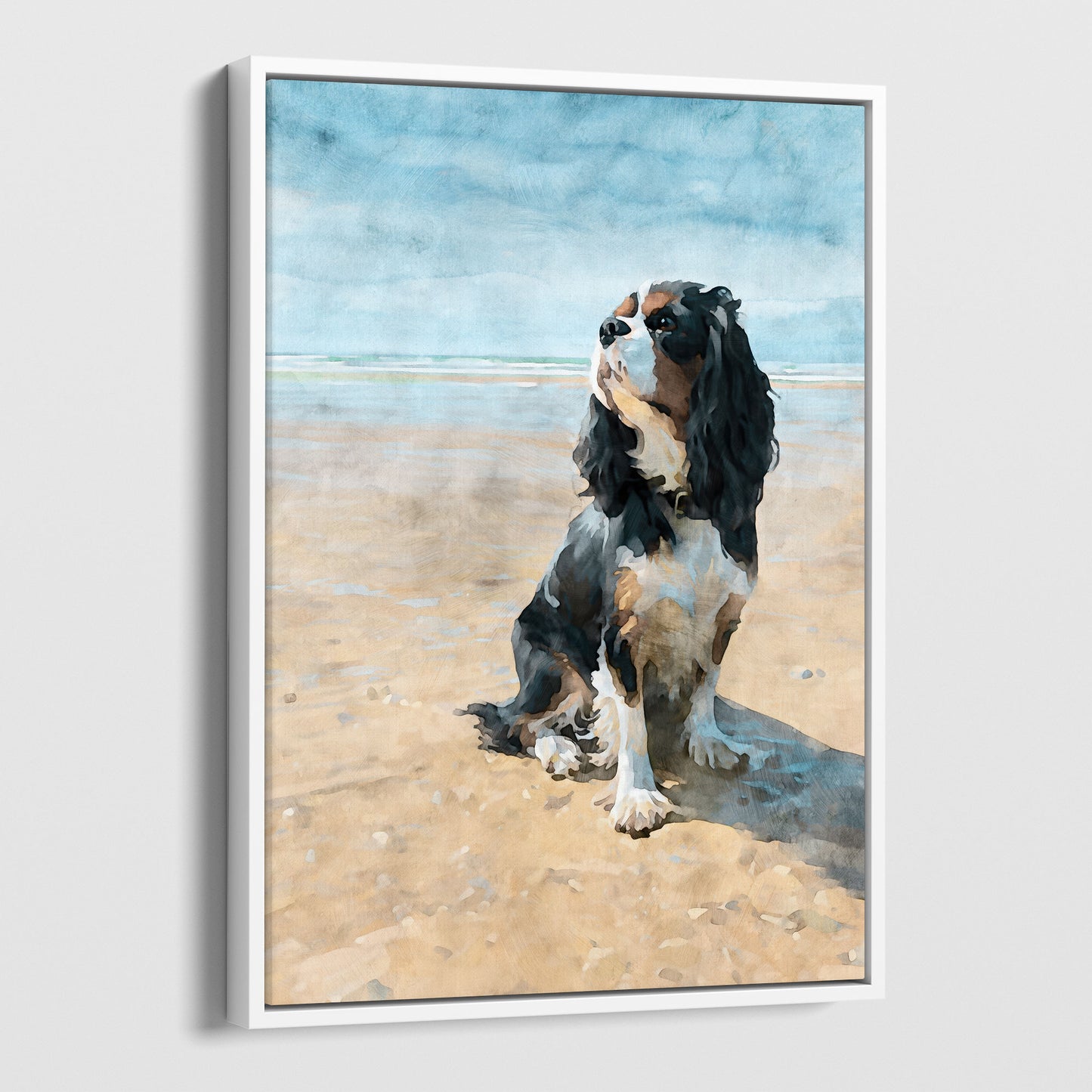 White float framed canvas print of a tricolor Cavalier King Charles spaniel on a beach
