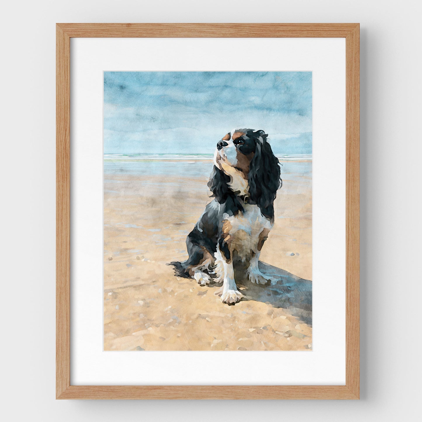 Framed artwork of a tricolor Cavalier King Charles spaniel on a beach with an oak wood frame.
