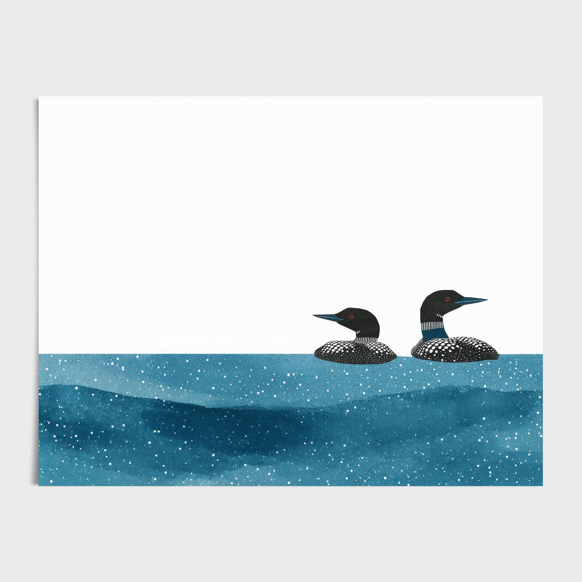 Minimalist art print featuring two common loons with black-and-white patterned plumage and red eyes, floating side by side in textured deep blue water speckled with white dots. The background is clean and white, creating a modern, airy contrast to the rich tones of the birds and water.